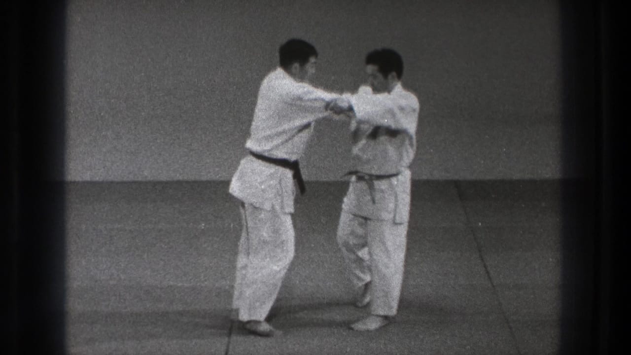 The black-belt practitioner appears to secure his partner's arm during a controlled karate defense demonstration in Tokyo.