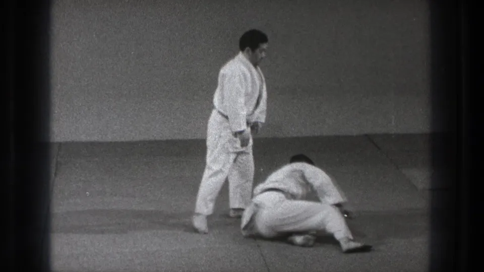 1971 Tokyo martial arts practice with one man in a white gi standing over another on a padded mat after a throw.