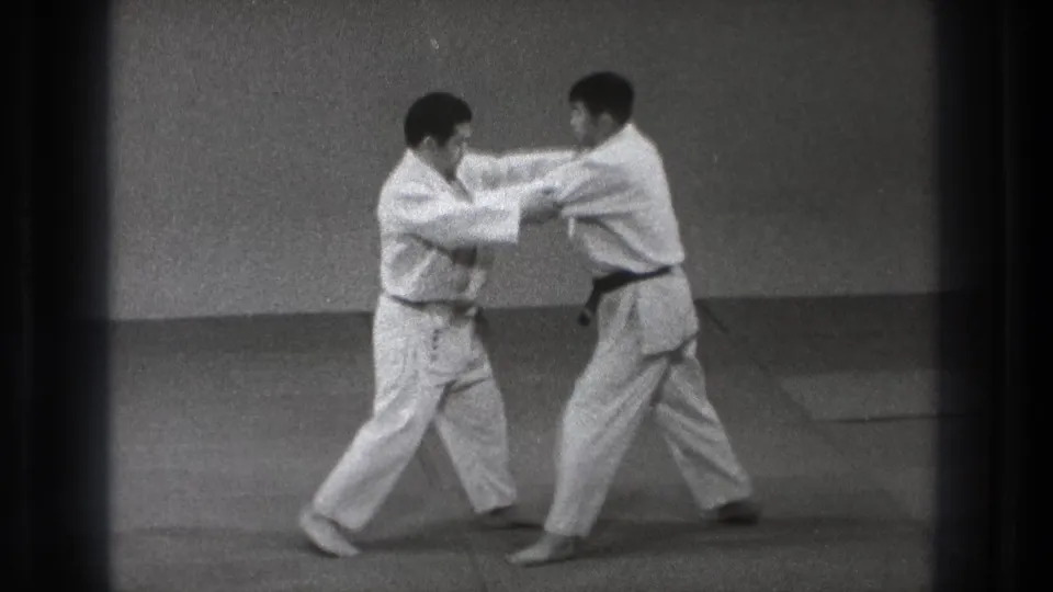 During the Tokyo judo practice, the two men maintain grips and shift their feet as the take-down setup develops.