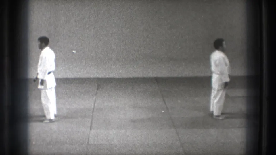 In the supplied 1971 Tokyo judo footage, two adult judoka stand at distance on a wide tatami practice area.