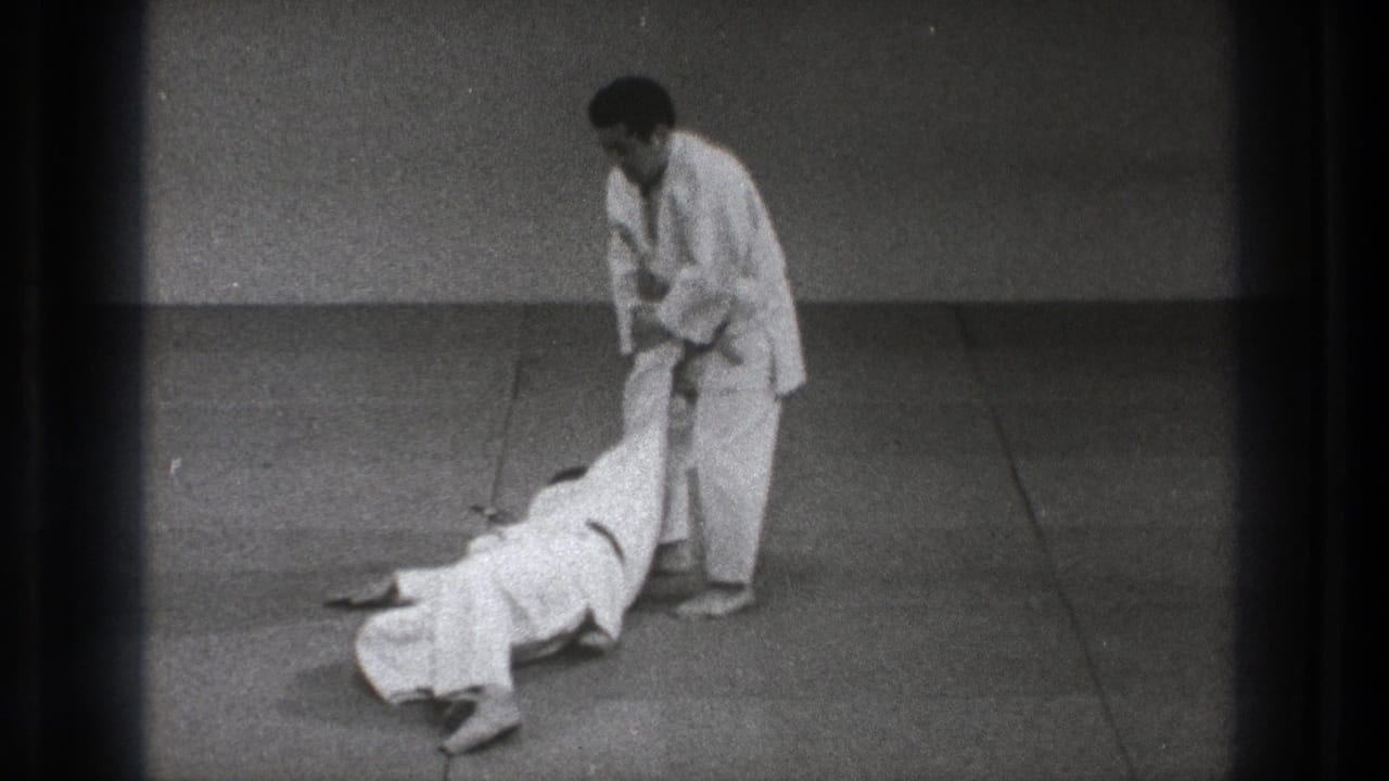 At the end of the technique, the thrown partner lies on the mat as the standing practitioner keeps a controlled hold in the Tokyo training scene.