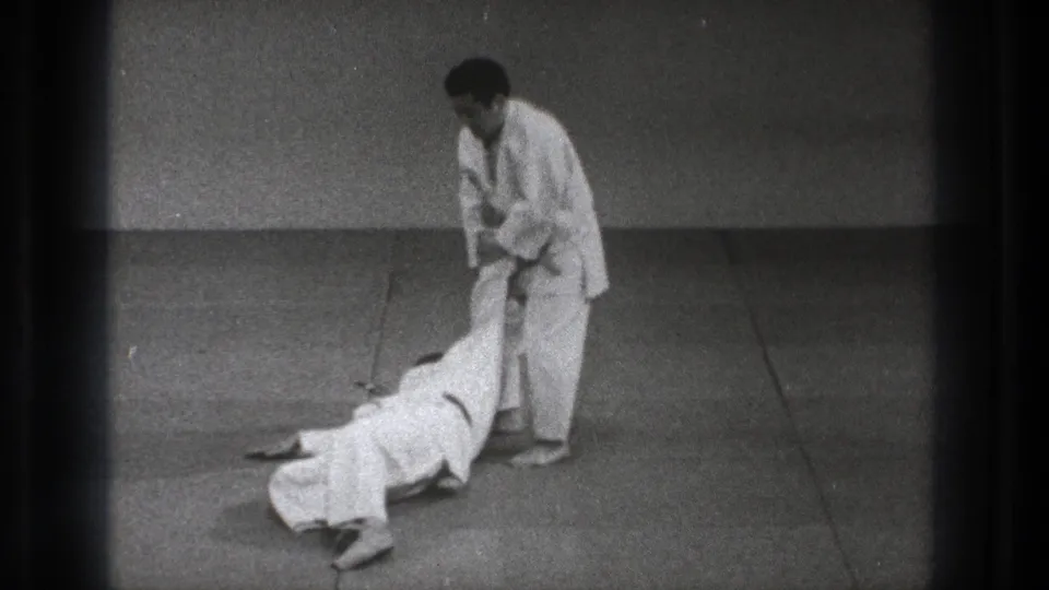 At the end of the technique, the thrown partner lies on the mat as the standing practitioner keeps a controlled hold in the Tokyo training scene.