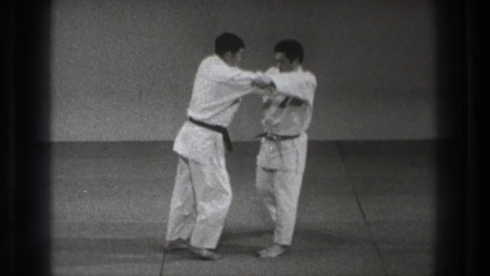 In the supplied 1971 Tokyo clip, two adult men in martial arts uniforms prepare for a technique on floor mats.