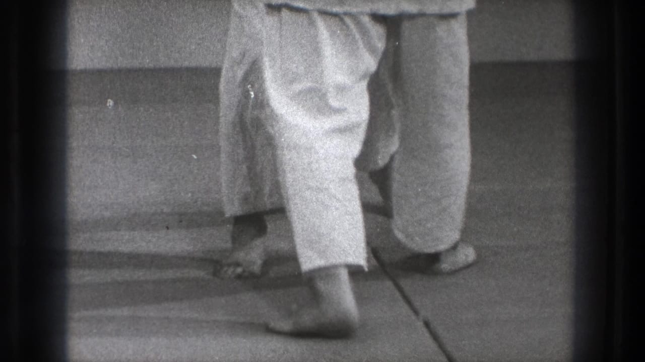Tokyo 1971 8mm frame showing barefoot martial arts practitioners in white trousers, cropped at leg level during close footwork.