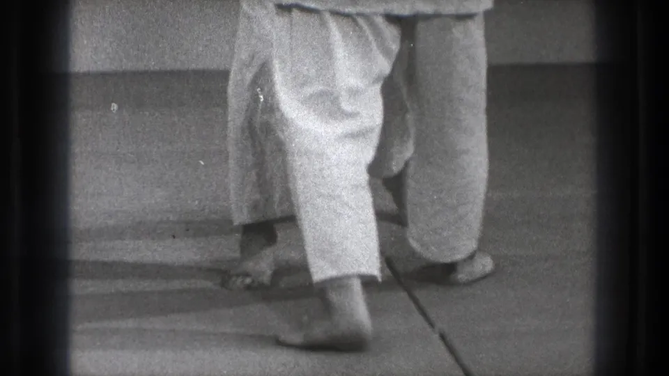 Tokyo 1971 8mm frame showing barefoot martial arts practitioners in white trousers, cropped at leg level during close footwork.