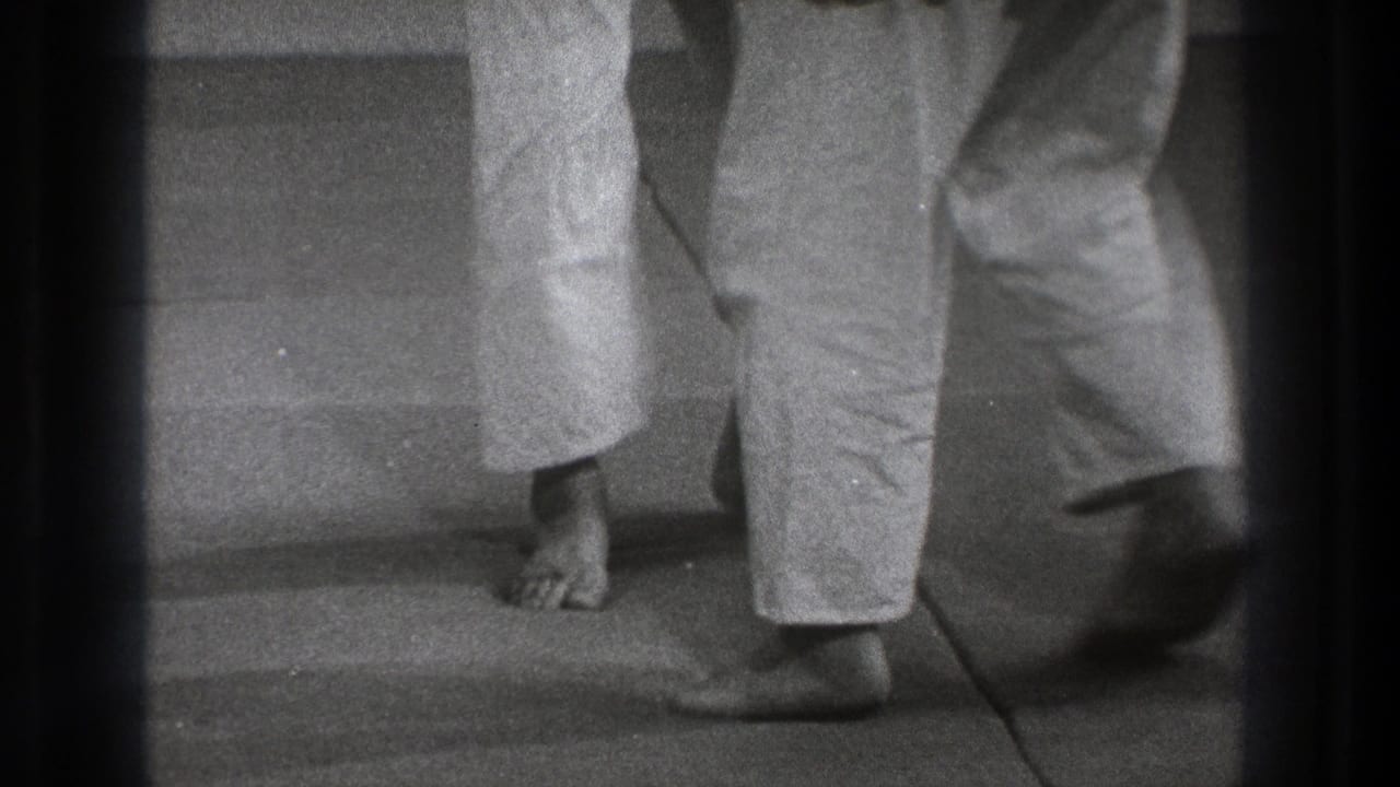 Bare feet and uniformed legs shift position during a close martial arts movement.