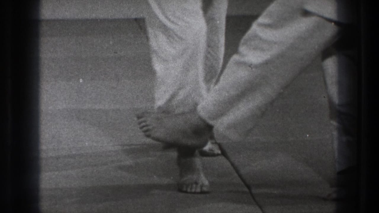 Tokyo 1971 8mm frame showing a barefoot martial arts participant dropping sideways near another practitioner's legs.