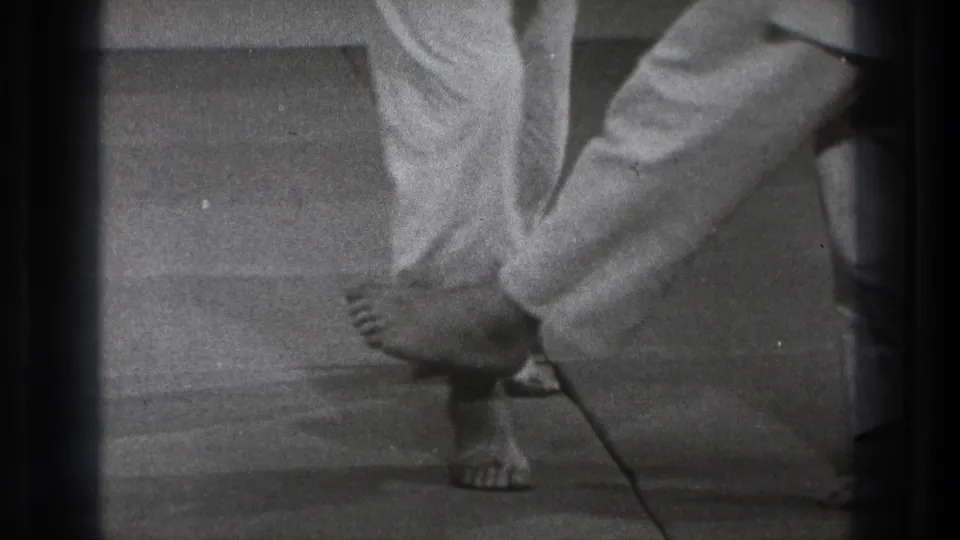 Tokyo 1971 8mm frame showing a barefoot martial arts participant dropping sideways near another practitioner's legs.
