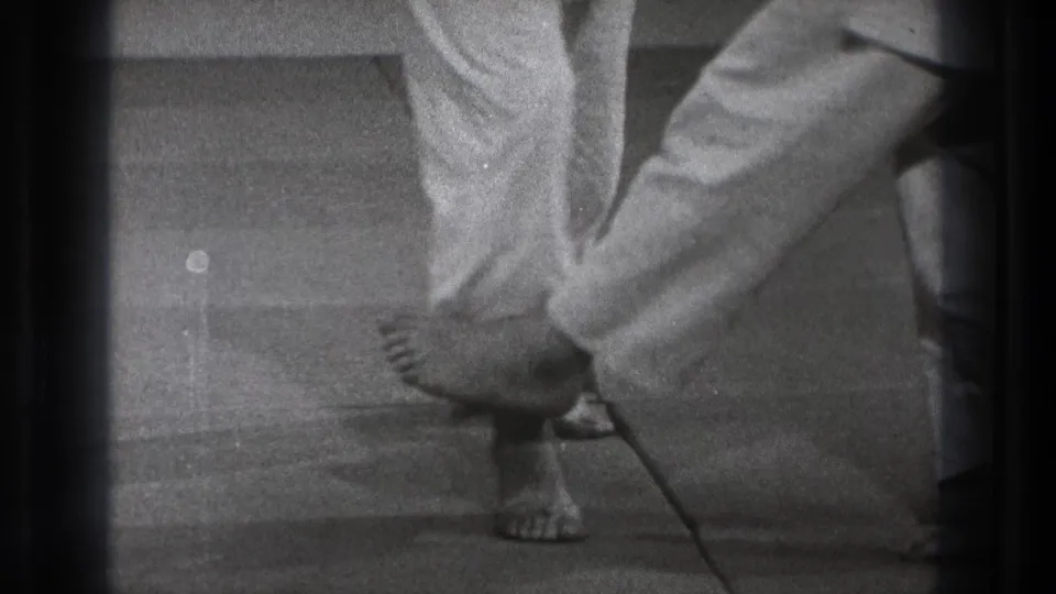 Tokyo 1971 black-and-white frame showing the end of a fall or sweep, with one practitioner low on the floor beside standing legs.