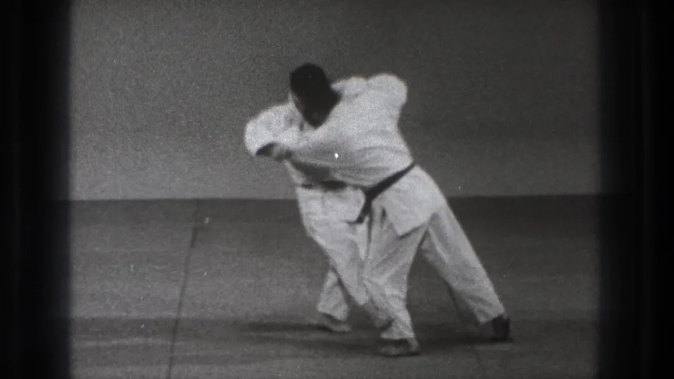 The final frame shows the pair leaning into a close-contact martial arts movement, with one man turning his body across the mat.