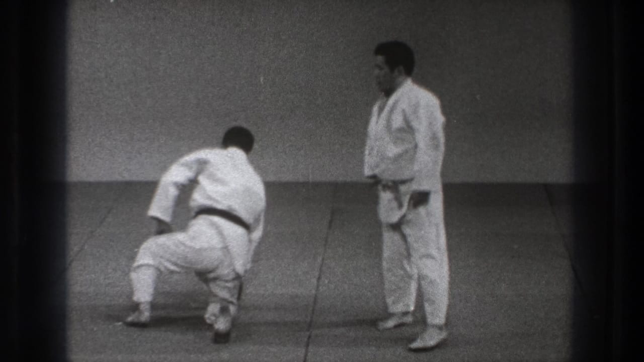 A 1971 Tokyo dojo view shows one adult practitioner pushing up from the mat as his partner in a white gi observes.