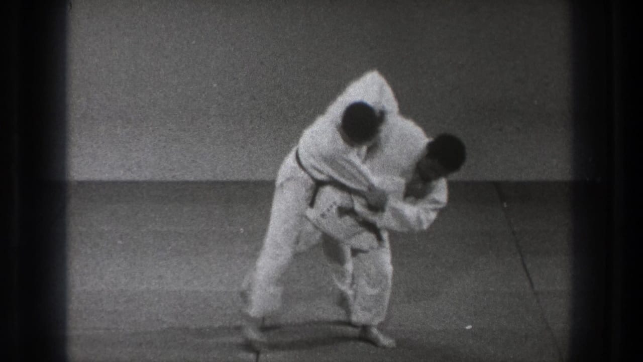In the Tokyo martial arts scene, the black-belt practitioner turns his body under his partner's grip as the throw begins.