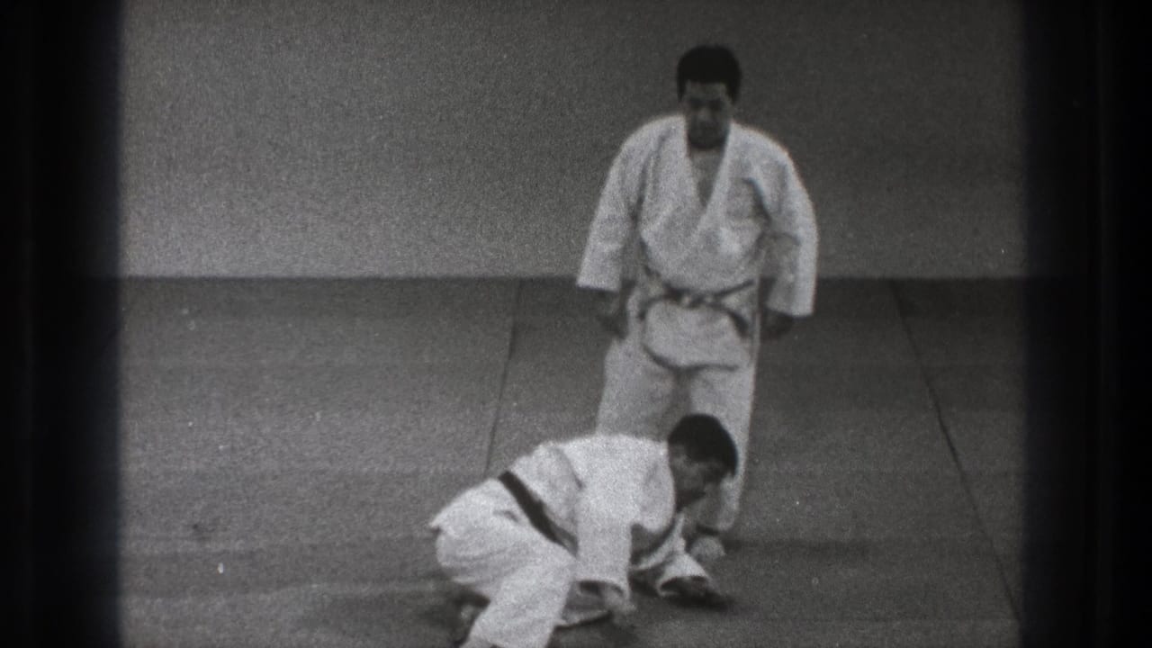 After the throw in the 1971 Tokyo martial arts footage, one man is down on hands and knees while his partner stands beside him.