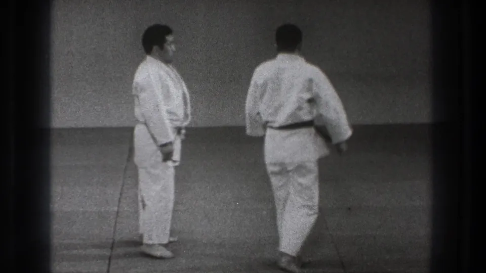 The two adult martial arts practitioners stand upright and move apart at the end of the 1971 Tokyo training demonstration.