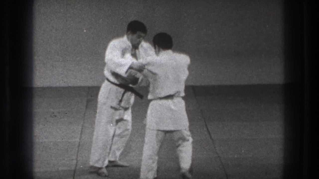 Two men in white judo uniforms grip each other on a mat.