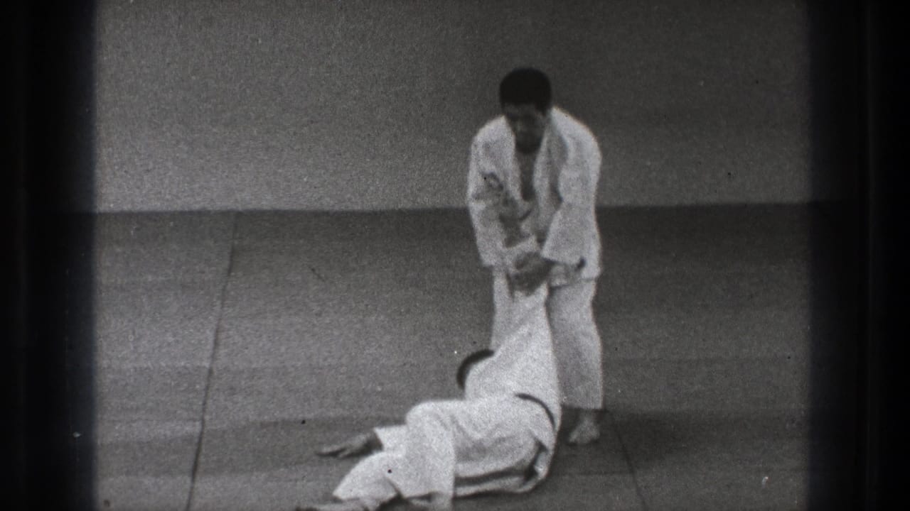 The 1971 Tokyo dojo scene ends with one practitioner standing over a partner on the mat after a completed judo throw.