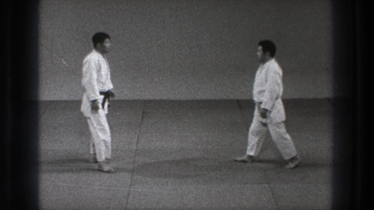 Two men in white martial arts uniforms face each other on a mat.