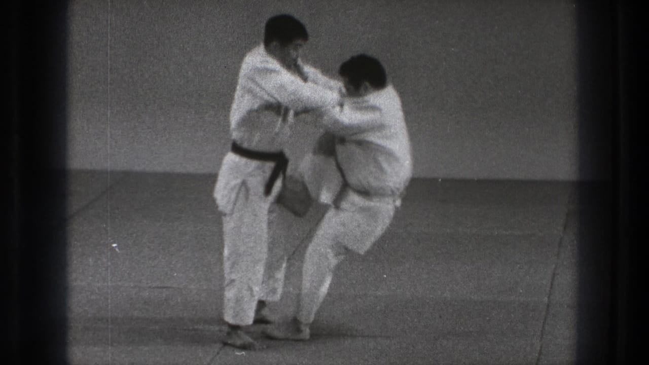 During the 1971 Tokyo practice, the black-belt practitioner lifts his partner from the mat as the body throw begins indoors.