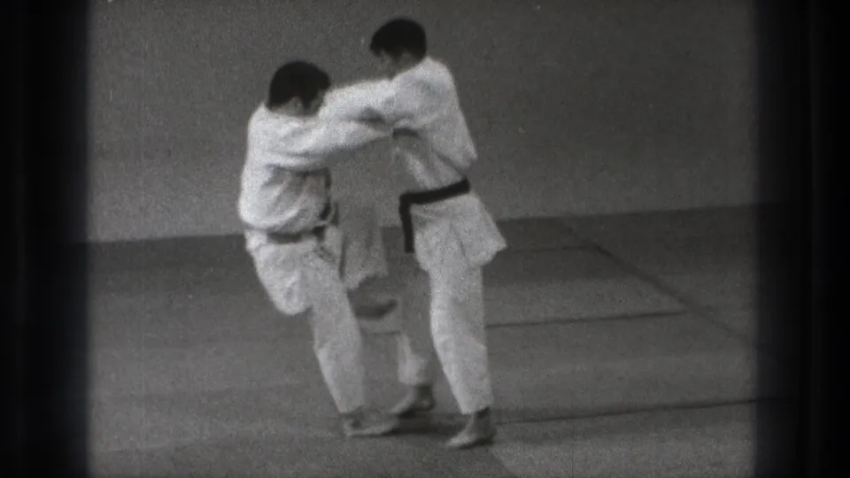 In 1971 Tokyo 8mm footage, one gi-clad practitioner turns in close as a judo-style throw begins.