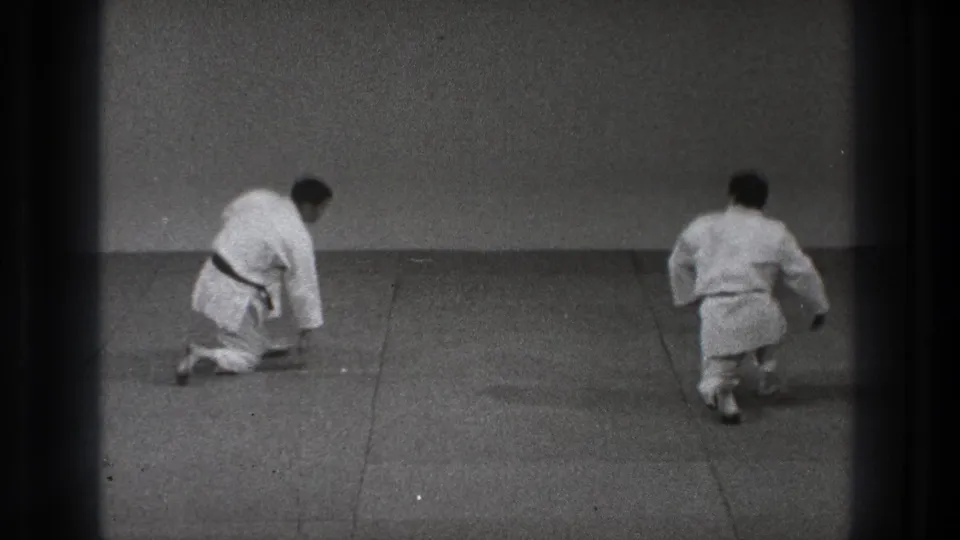 Two men in white karate gi bow toward each other on a mat in Tokyo, Japan, 1971 footage.