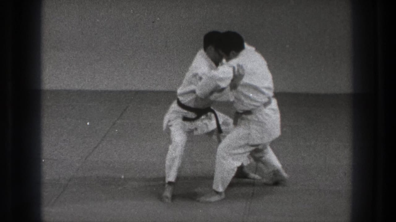 The practitioners stay low while gripping each other, suggesting the middle phase of a throw or takedown demonstration.