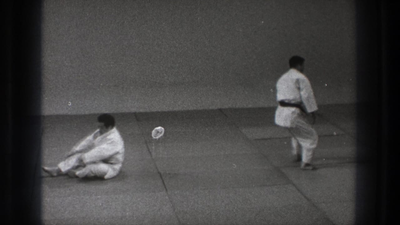 After the throw, one practitioner sits on the mat while the other steps across the training area in the 1971 Tokyo footage.