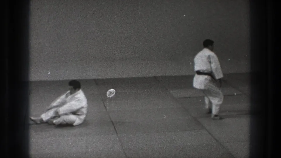 After the throw, one practitioner sits on the mat while the other steps across the training area in the 1971 Tokyo footage.