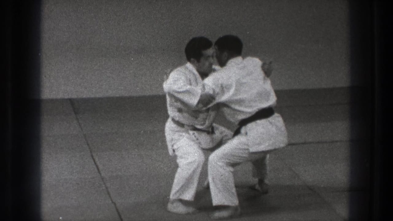 The Tokyo judo footage shows two adult practitioners gripping each other in a low, controlled grappling position.