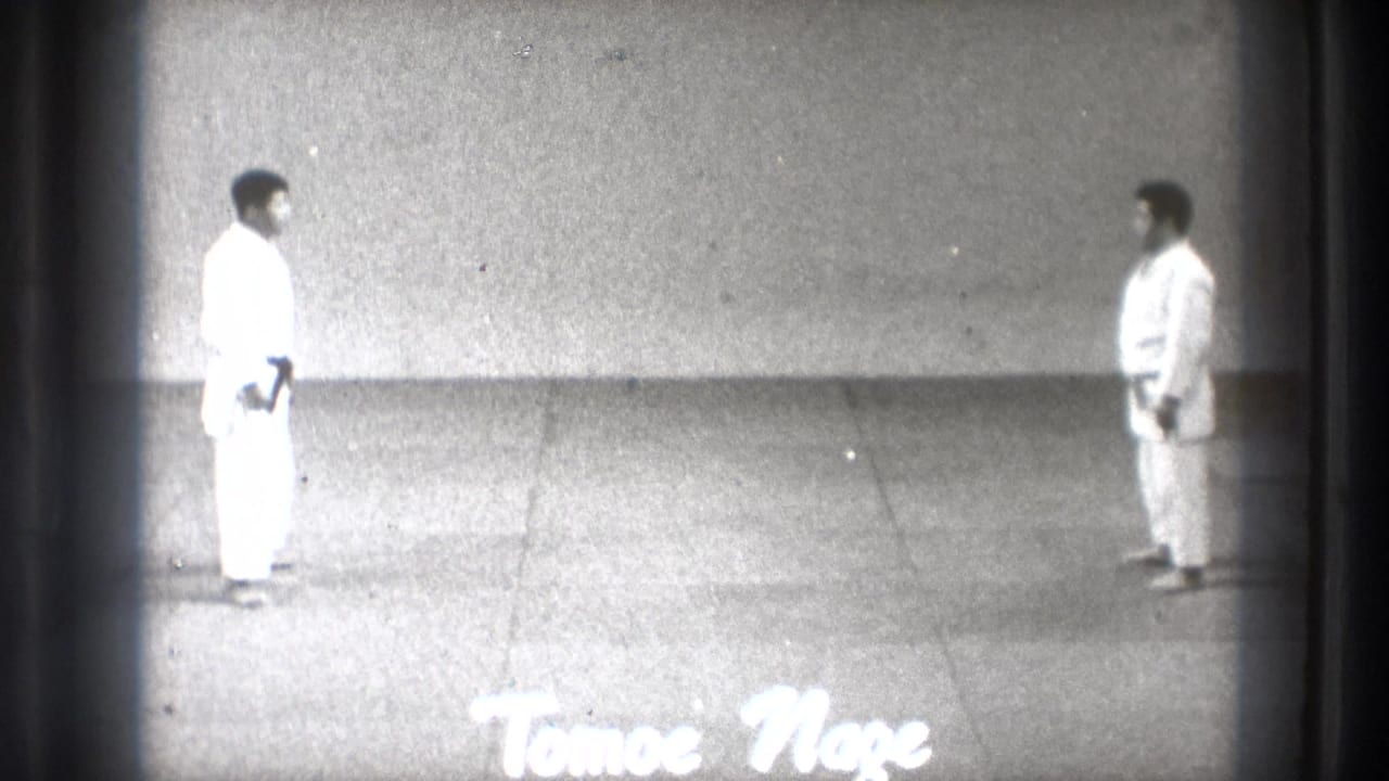 Two men in white gi face each other across a mat with Tomoe Nage text at the bottom.