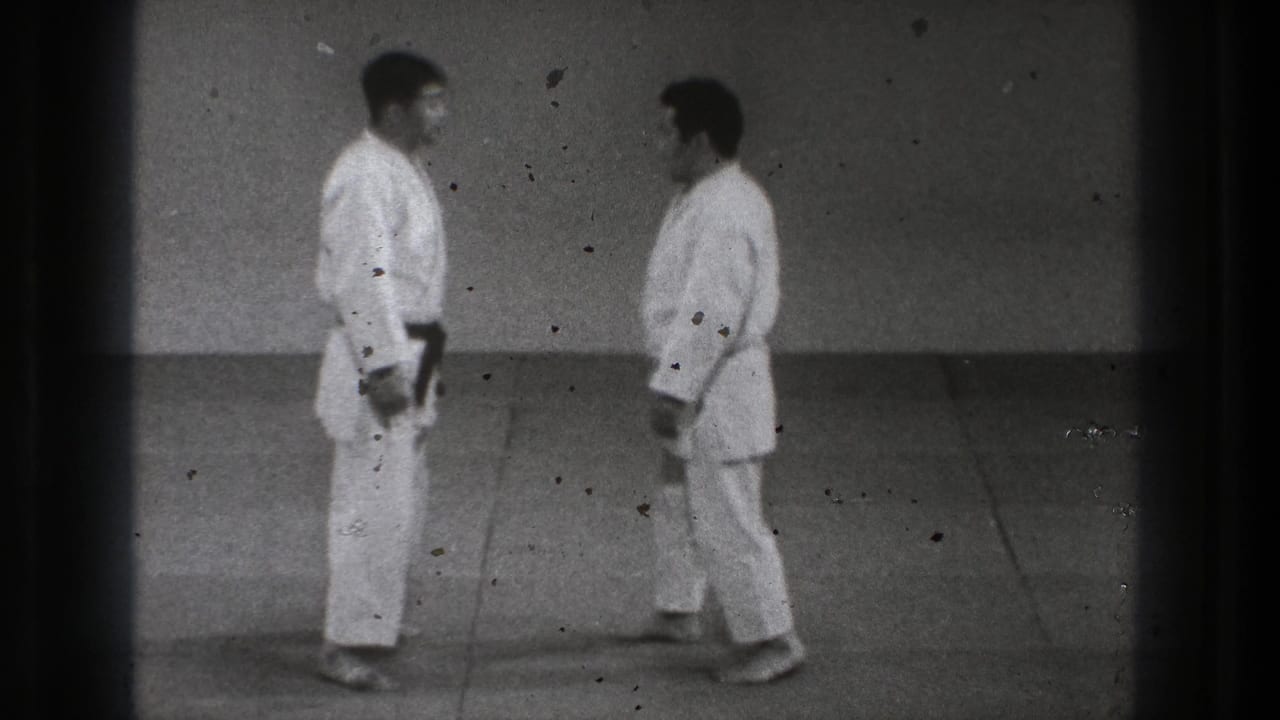 1971 Tokyo 8mm frame with two practitioners standing face to face in white gi during a Tomoe Nage demonstration setup.