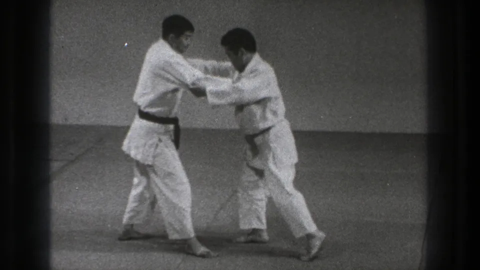 In the 1971 Tokyo footage, one practitioner steps in while both men keep arm contact during the grappling technique.