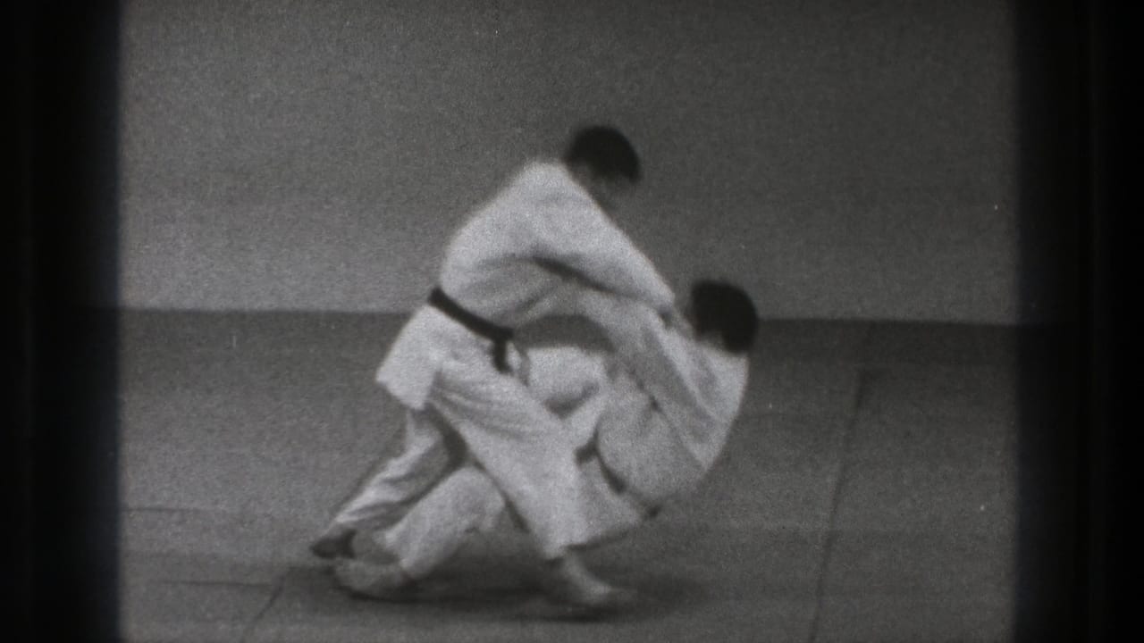 The throw resolves with one man on the mat and the black-belt practitioner standing above him in the short 1971 Tokyo training sequence.