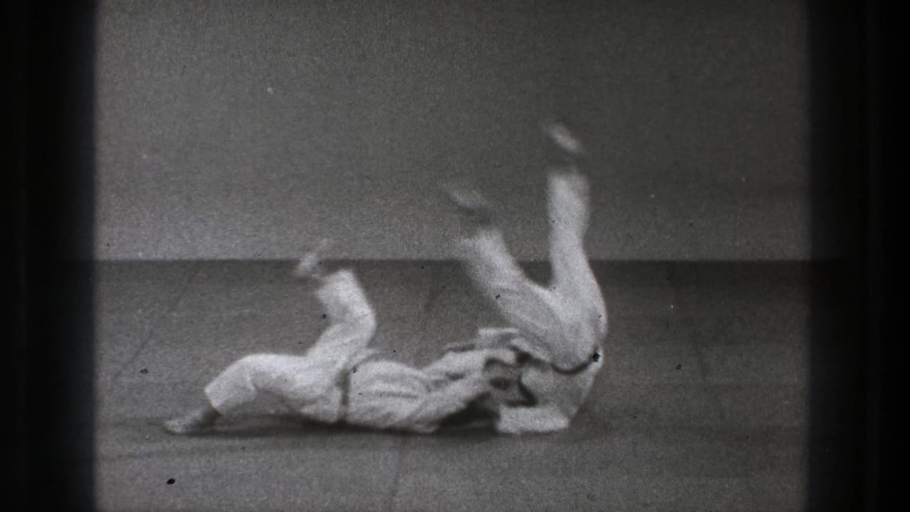 Tokyo 1971 8mm frame showing a judo throw with one adult practitioner airborne above the mat.