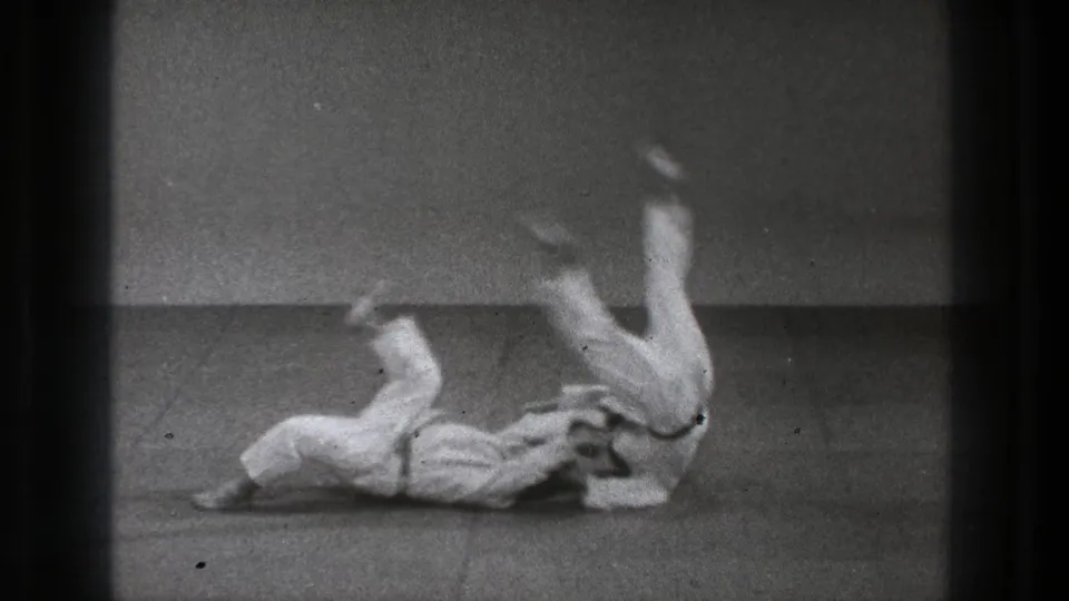 Tokyo 1971 8mm frame showing a judo throw with one adult practitioner airborne above the mat.