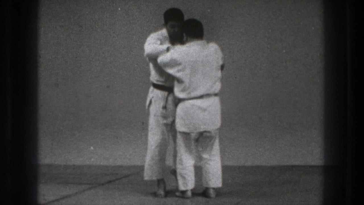 Tokyo 1971 8mm frame of two adult judo practitioners in white gi holding a close grappling position.