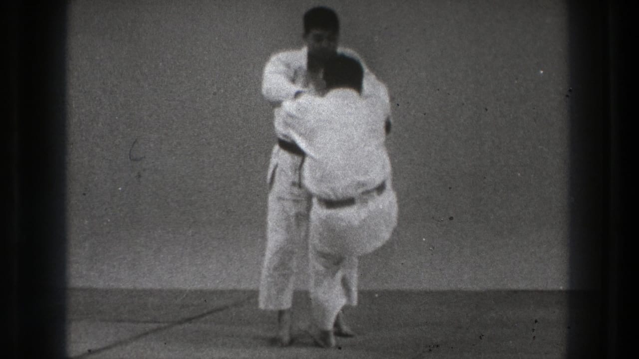 Two men in white gi face each other on a mat during a martial arts drill.