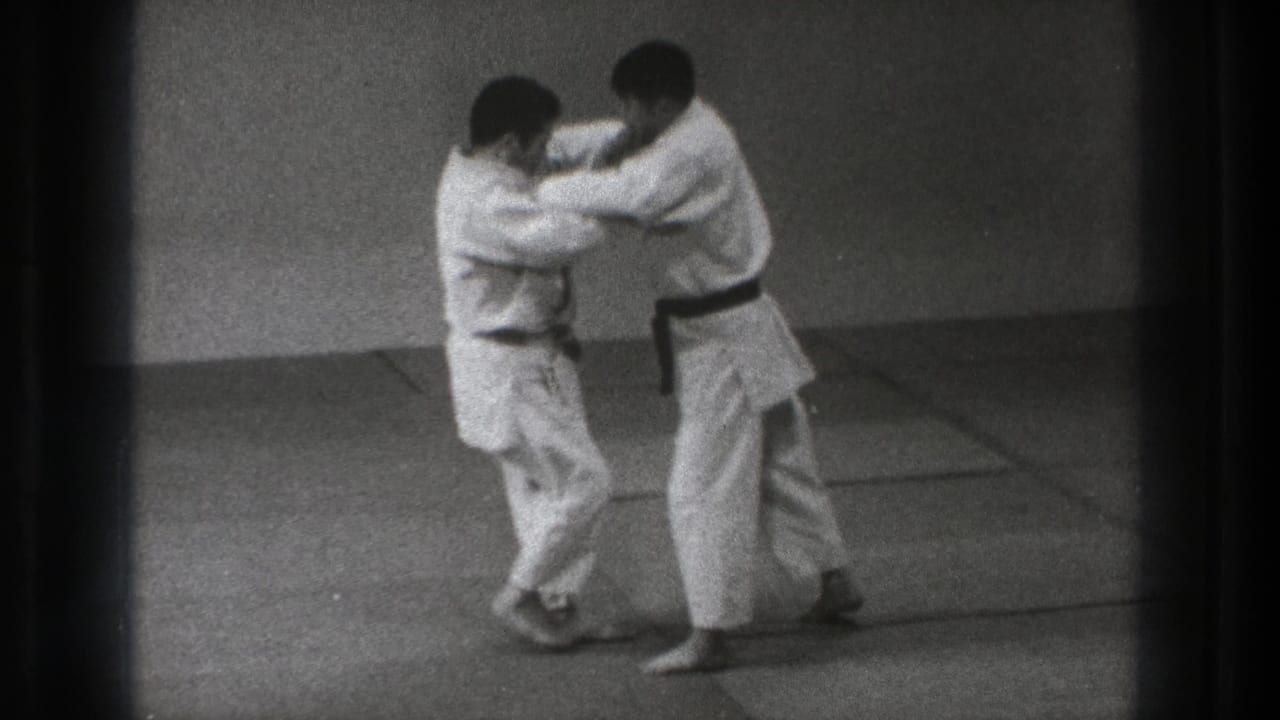 The final frame shows the two adult men in white gi maintaining grips as they practice on the dojo mat in archival 1971 Tokyo footage.