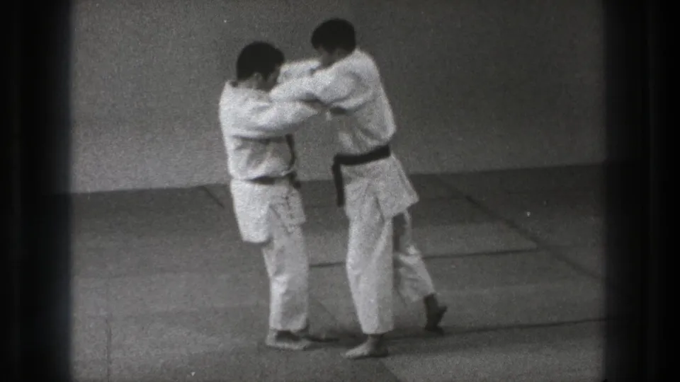 In Tokyo, Japan, 1971, two men in white judogi stand on mats while beginning a judo technique demonstration.