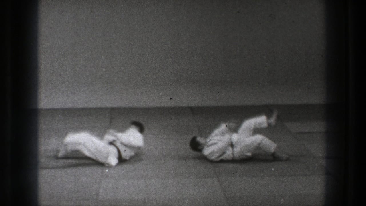 The 1971 Tokyo footage shows both practitioners on the padded floor after the throw, rolling through the landing.