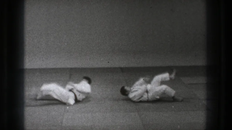 The 1971 Tokyo footage shows both practitioners on the padded floor after the throw, rolling through the landing.