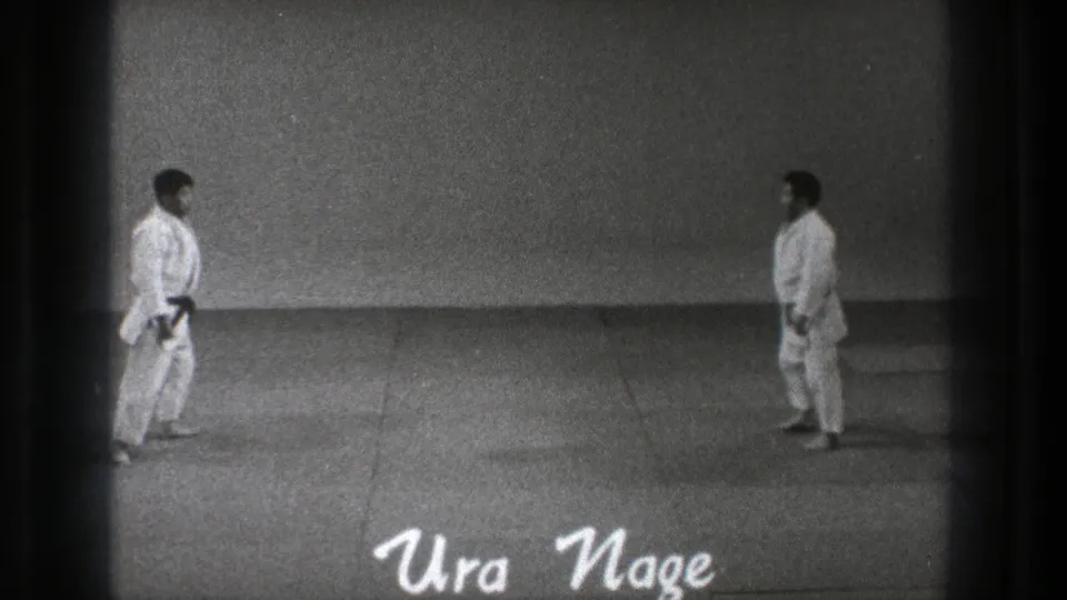 1971 Tokyo 8mm frame with two judo practitioners facing each other across the mat before the Ura Nage demonstration.