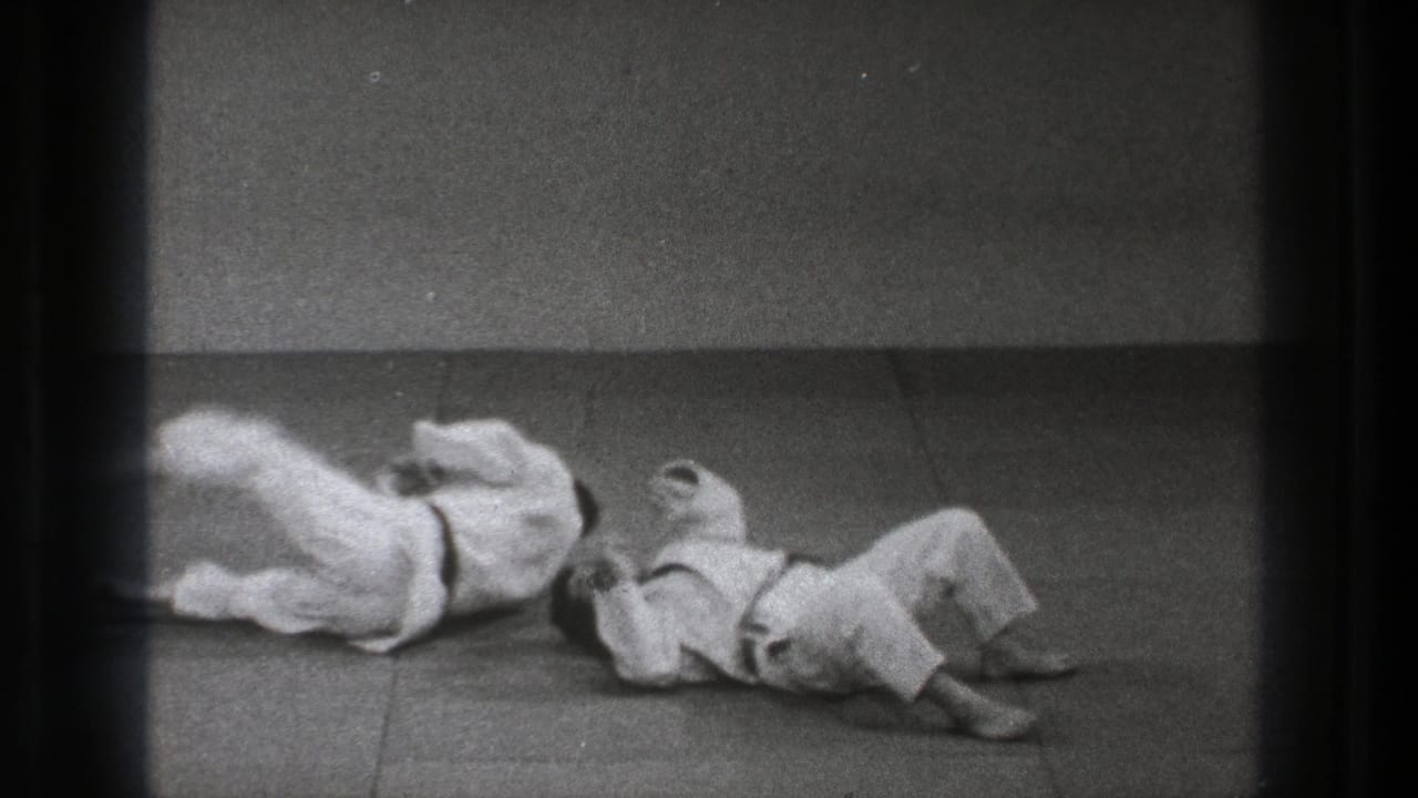 At the end of the 1971 Tokyo slow-motion throw, both uniformed practitioners are down on the indoor mat after impact.