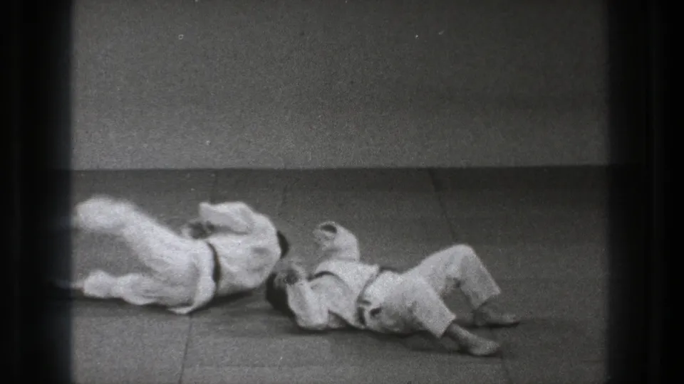At the end of the 1971 Tokyo slow-motion throw, both uniformed practitioners are down on the indoor mat after impact.