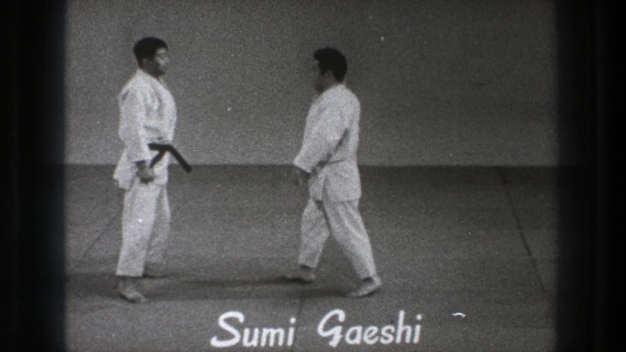Two adult practitioners pause opposite each other on the mat as the Sumi Gaeshi label appears in the 1971 Tokyo martial arts clip.