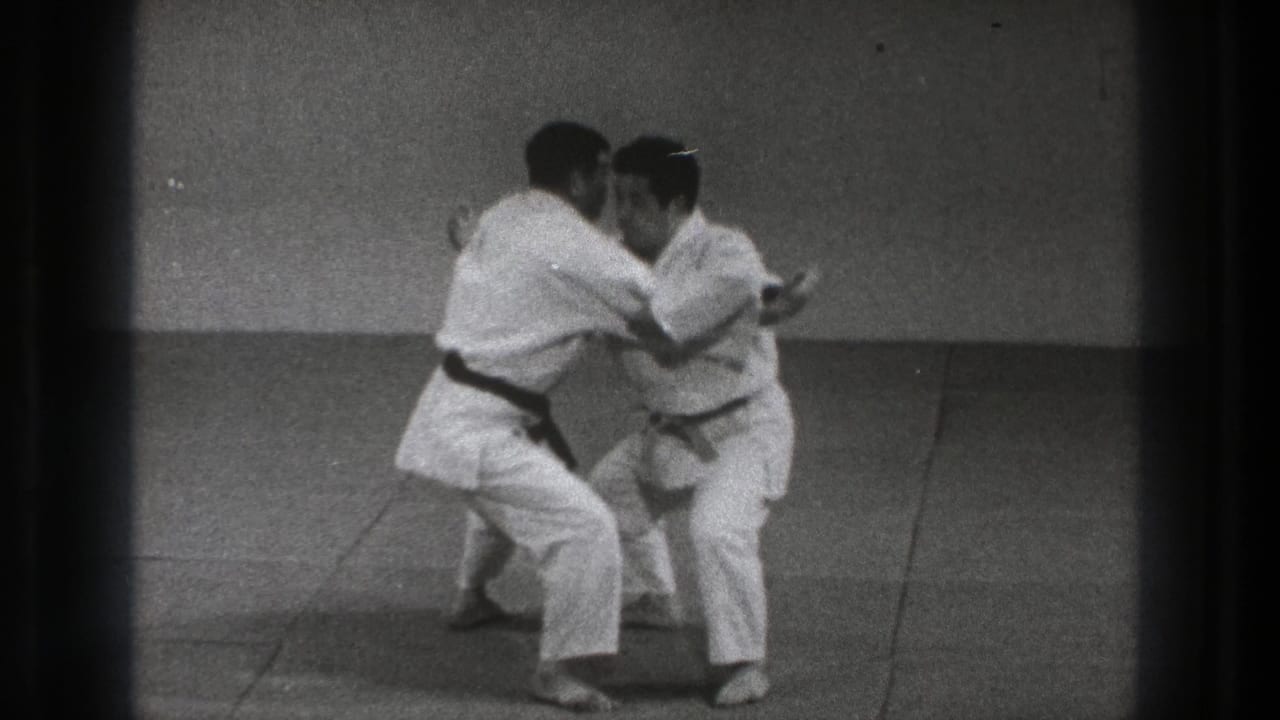 The practitioners grip each other and drop into the throwing motion during the Sumi Gaeshi demonstration in the 1971 Tokyo clip.