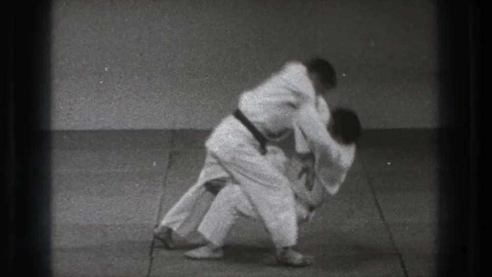 Near the end of the 1971 Tokyo throw sequence, one practitioner falls sideways while the other remains standing.
