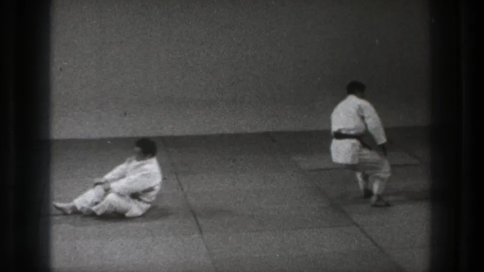 The final frame shows one judo practitioner seated on the tatami while another in a white gi walks away across the dojo.