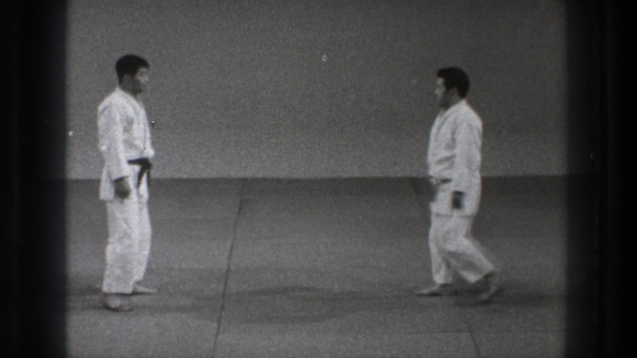 Two adult men in white gi move into closer range on the matted floor during a martial-arts demonstration in the 1971 Tokyo clip.