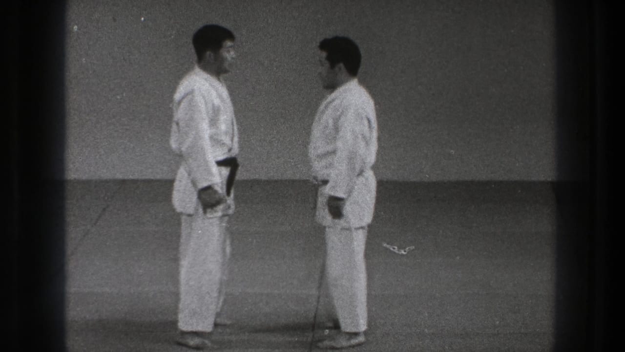 Two men in white karate gi stand facing each other on a mat.