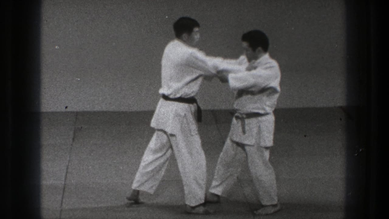 The partner drill continues as two men in gi hold arm contact and shift weight across the mat in the Tokyo 1971 clip.
